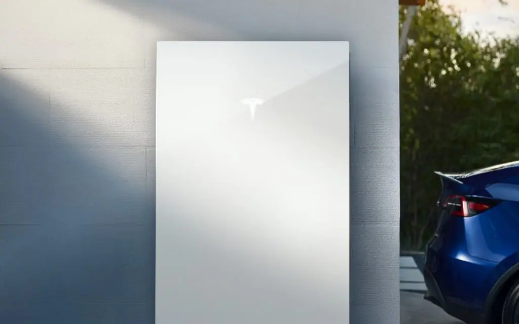 Wall-mounted home battery installed beside an electric vehicle in a garage